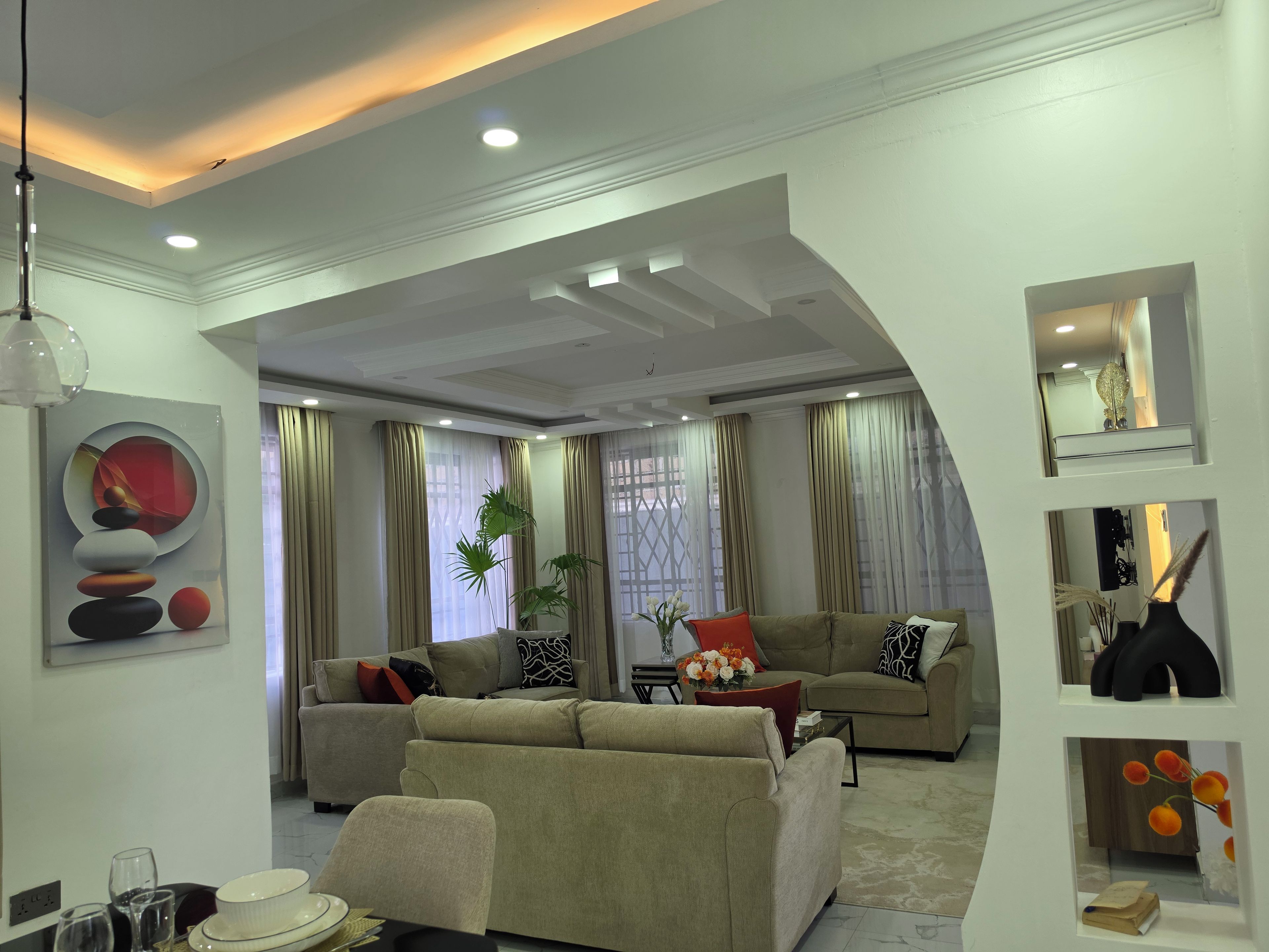 A modern living room with a sectional sofa, a coffee table, and a dining area with chairs and a table.