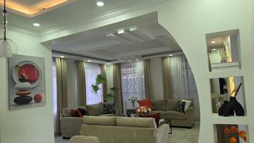 A modern living room with a sectional sofa, a coffee table, and a dining area with chairs and a table.