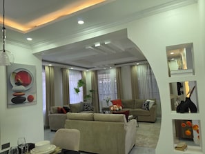 A modern living room with a sectional sofa, a coffee table, and a dining area with chairs and a table.