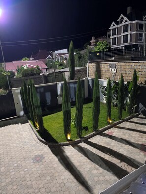 A residential area with a paved walkway, a stone wall, and a well-maintained lawn with trimmed hedges. - Almara Residence Spacious 4BR Private Home (Nakuru)