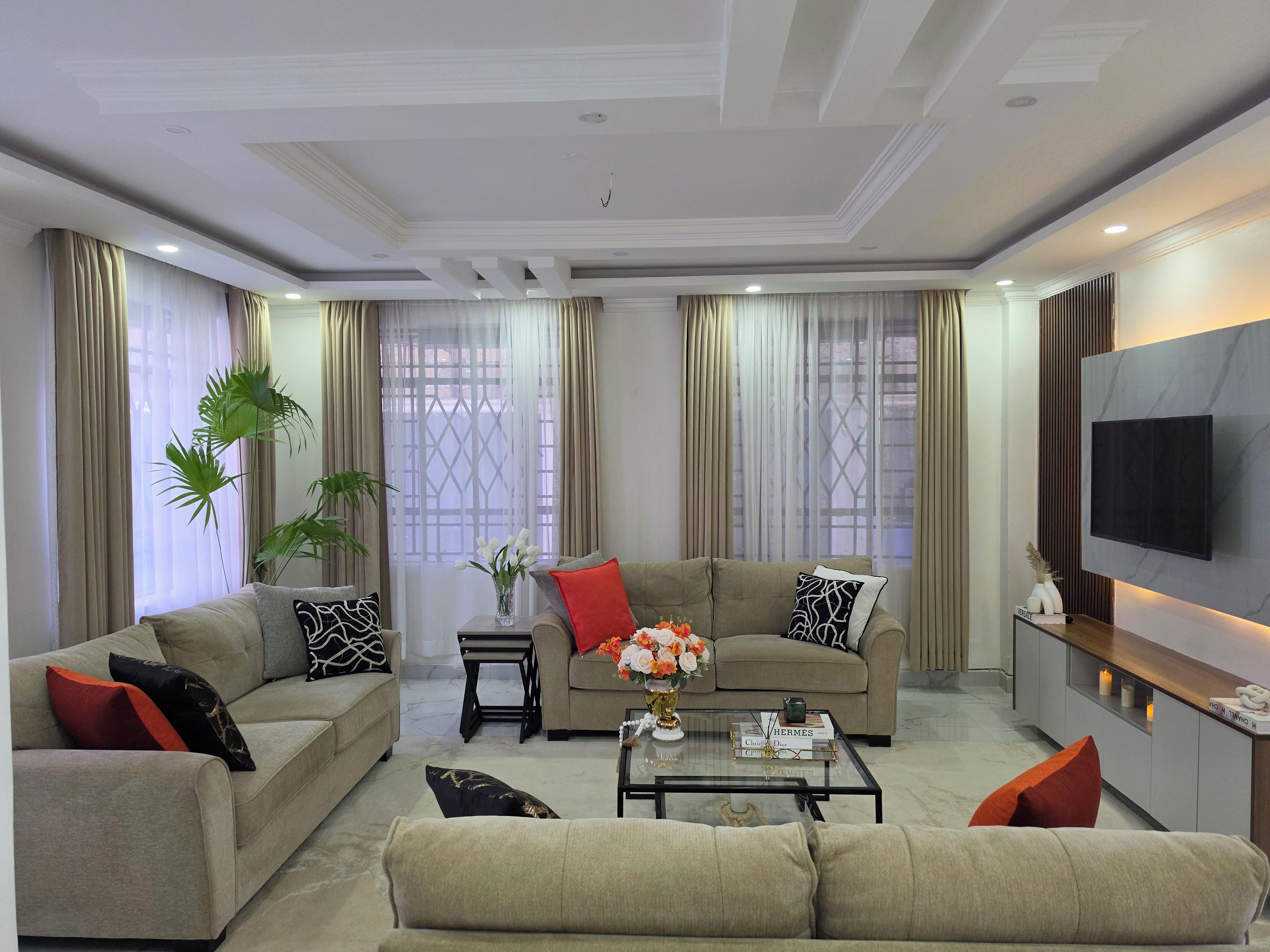 A modern living room with a sofa set, a coffee table, and a TV mounted on the wall.