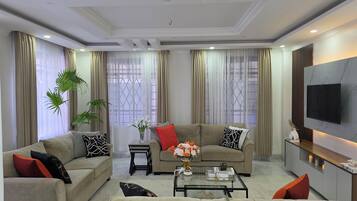 A modern living room with a sofa set, a coffee table, and a TV mounted on the wall.