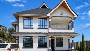 Une maison à deux étages avec un balcon, un garage et une allée.