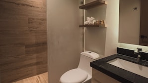 A modern bathroom with a toilet, a sink, and a mirror. - Depa de lujo en Playa del carmen (Playa del Carmen)