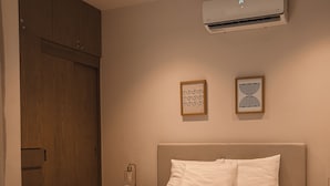 A bedroom with a bed, a wardrobe, an air conditioning unit, and two wall-mounted artworks. - Depa de lujo en Playa del carmen (Playa del Carmen)
