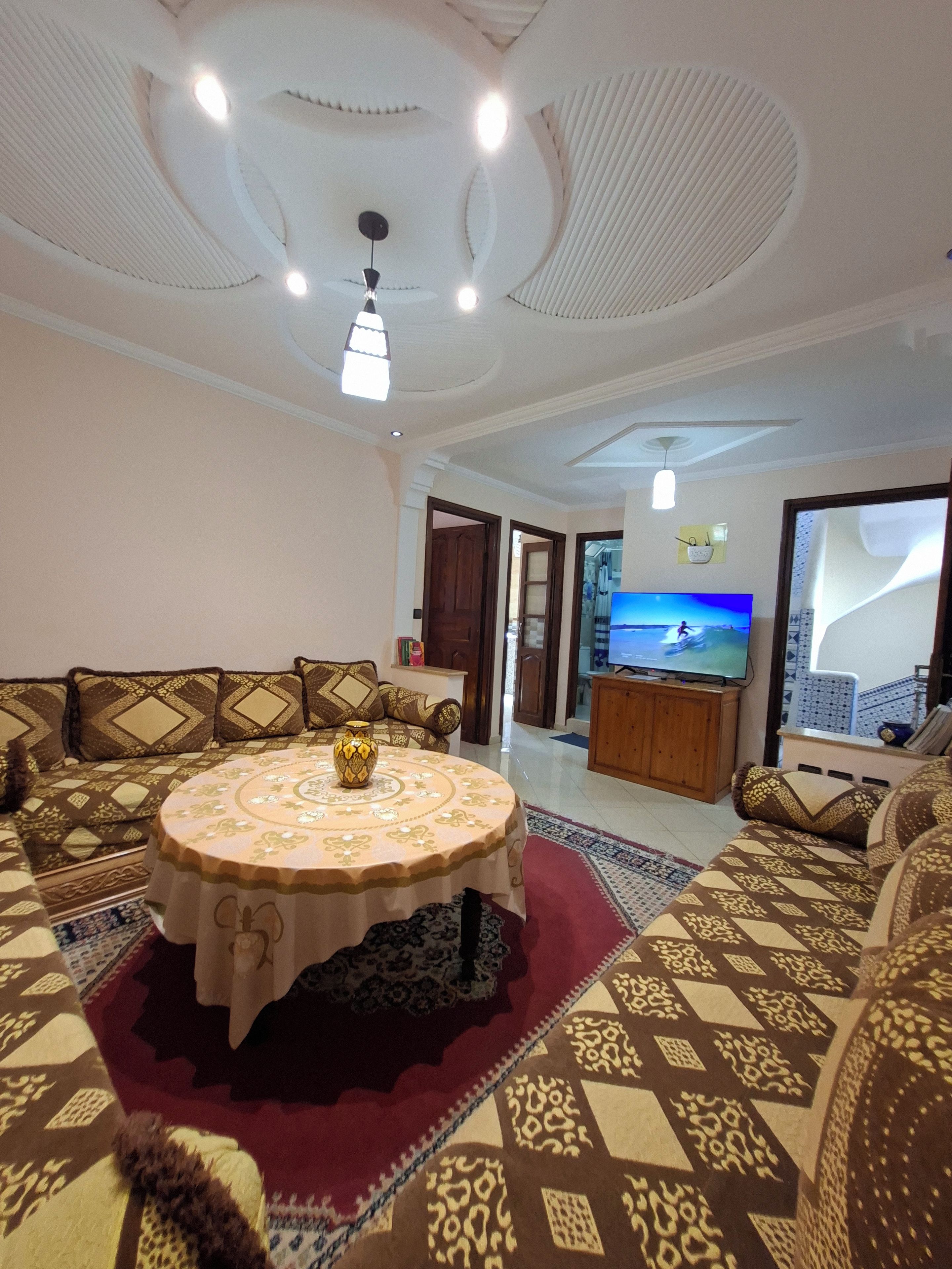 A living room with a sofa set, a round coffee table, and a television.