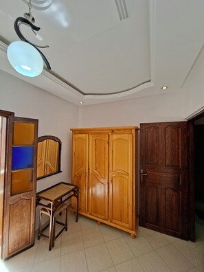 Ein Zimmer mit Schreibtisch, Kleiderschrank und Spiegel.