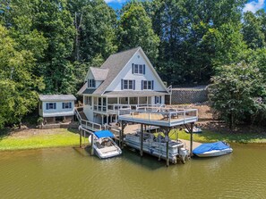 A two-story house with a dock and a boat. - Amazing One of a kind 3 Bedroom Lakeside Chalet with Optional Boat Rental (Rock Hill)