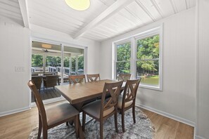 A dining area with a wooden table and chairs, large windows with a view of greenery, and a ceiling fan. - Amazing One of a kind 3 Bedroom Lakeside Chalet with Optional Boat Rental (Rock Hill)
