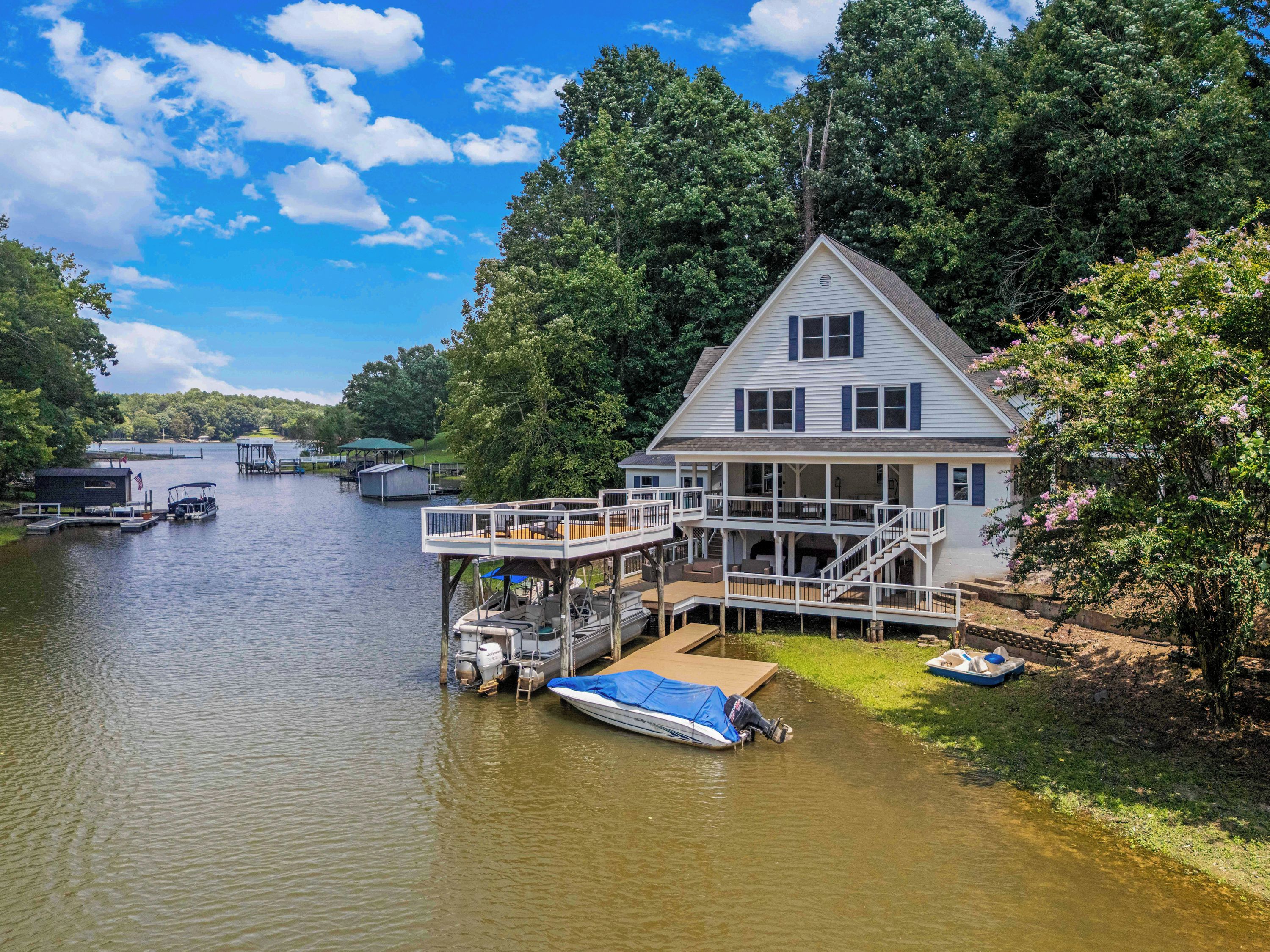 A house with a dock and a boat, surrounded by trees and a lake.