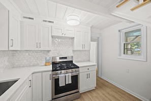 A kitchen with white cabinets, a stainless steel stove, and a window with a view of greenery. - Amazing One of a kind 3 Bedroom Lakeside Chalet with Optional Boat Rental (Rock Hill)