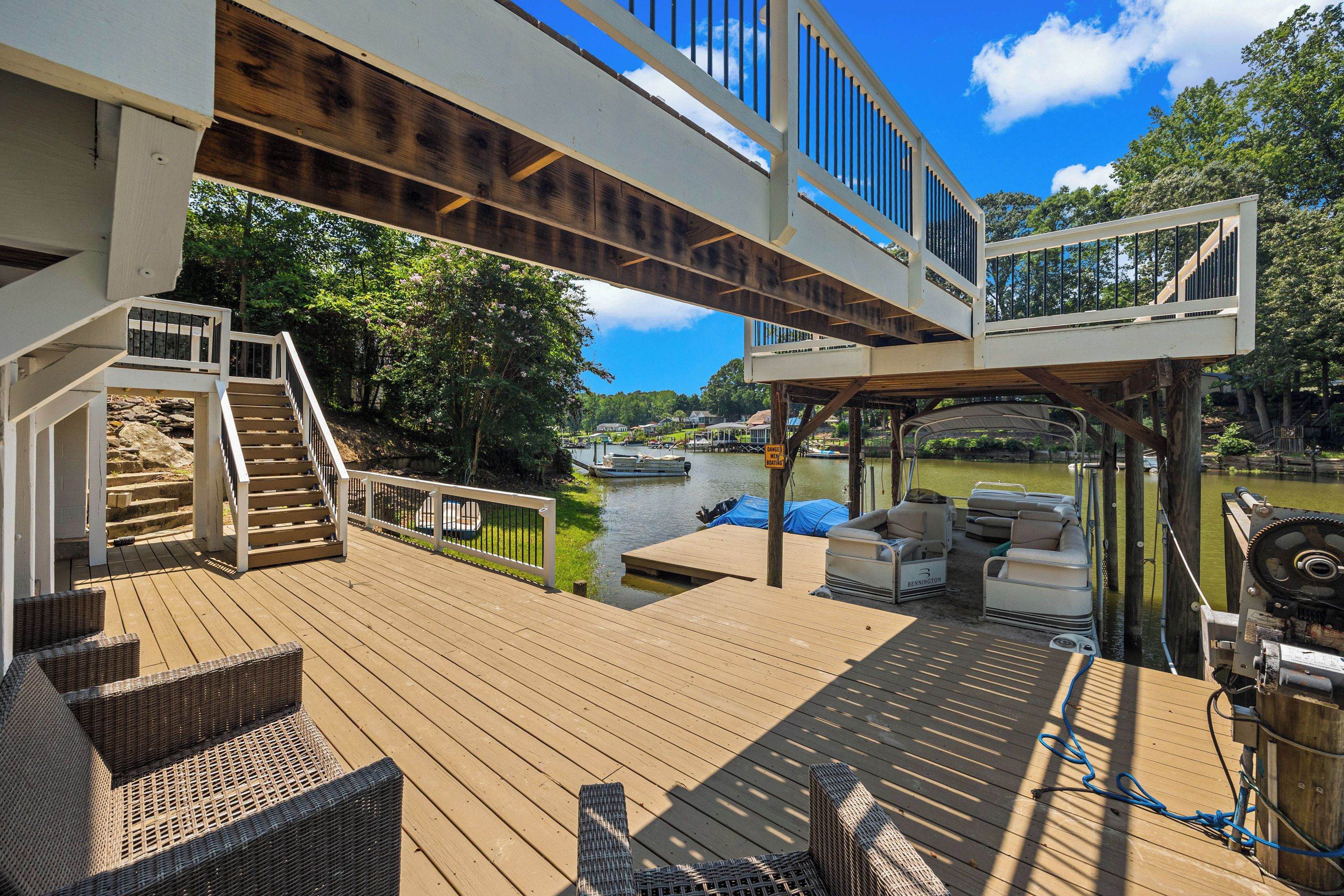 A wooden deck with outdoor furniture, a boat dock, and a river view.