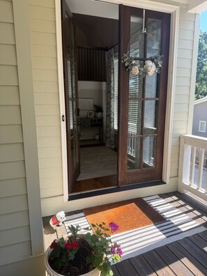 A wooden front door with glass panels, a porch with a striped rug, and a potted plant with flowers. - Marvelous 5-bedroom house with tons of space in 5 Points (Athens)