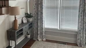 A staircase with wooden balusters, a grey console table with a lamp, a potted plant, and a window with blinds. - Marvelous 5-bedroom house with tons of space in 5 Points (Athens)
