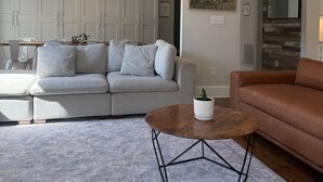 A living room with a grey sofa, a brown leather couch, and a coffee table with a plant. - Marvelous 5-bedroom house with tons of space in 5 Points (Athens)