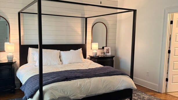 A four-poster bed with a dark frame, white bedding, and a dark blue patterned rug. - Marvelous 5-bedroom house with tons of space in 5 Points (Athens)