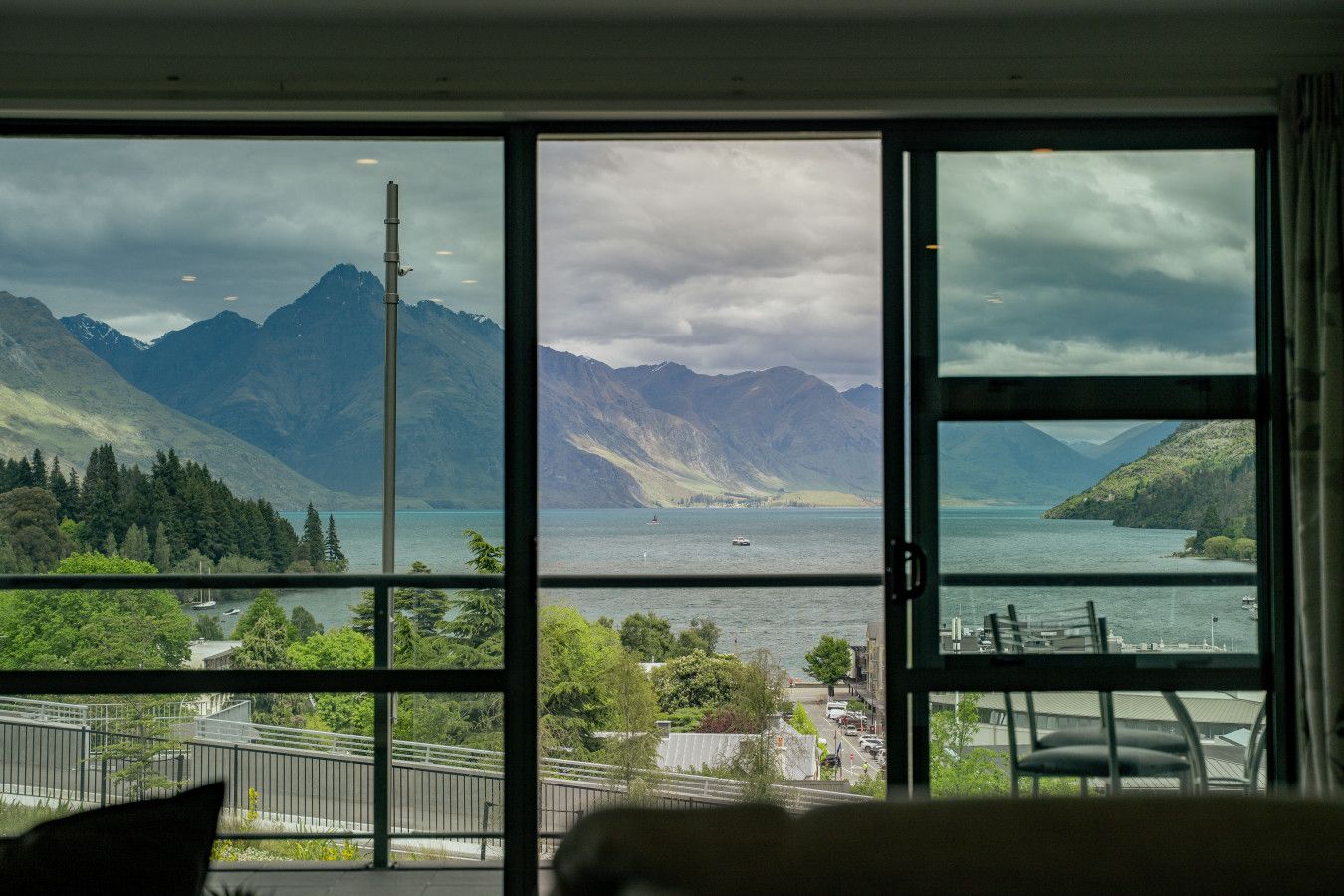 A room with a large window offering a view of a lake and mountains.