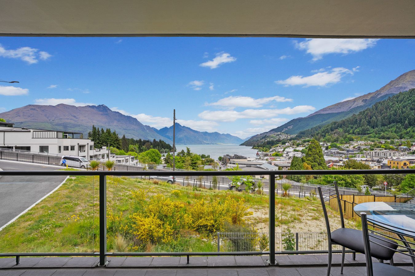 A balcony with a view of a lake, mountains, and a town.