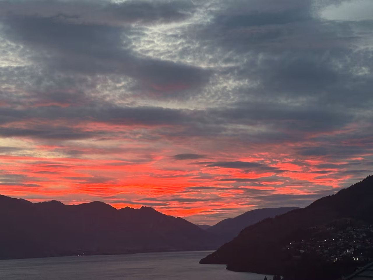 Eine Berglandschaft mit einem Gewässer und einem Sonnenuntergangshimmel.