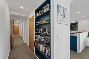 Ein Flur mit Bücherregal, einer Tür und einem Küchenbereich.
