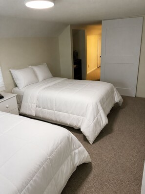 A bedroom with two beds, a nightstand, and a closet.