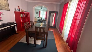 Ein Essbereich mit Klavier, einem roten Bücherregal und Blick in einen anderen Raum.
