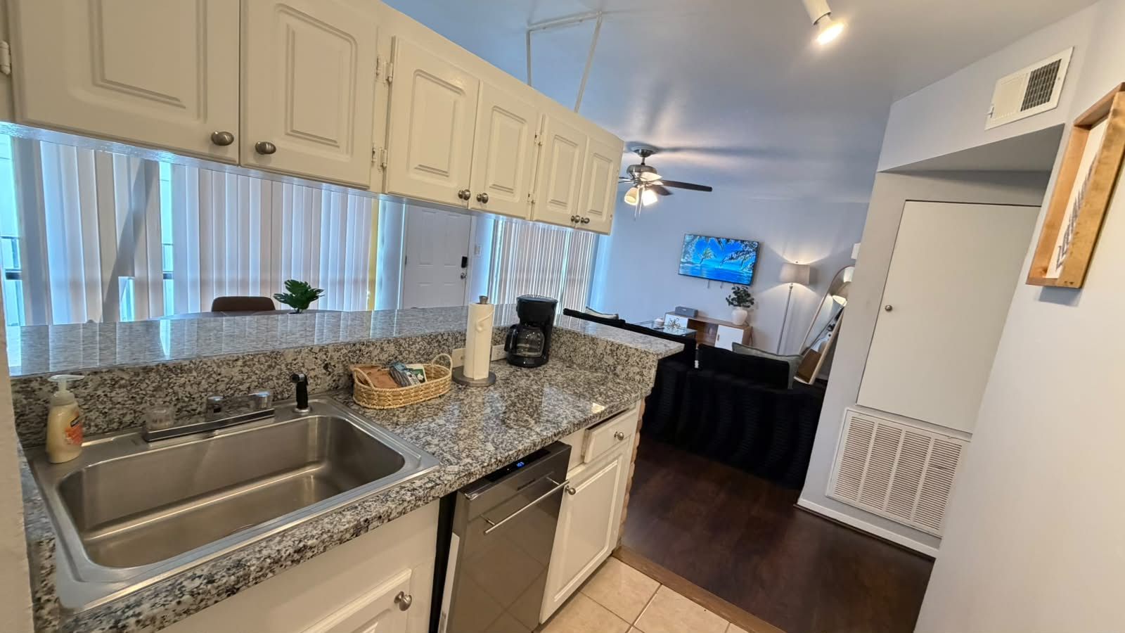 A kitchen with granite countertops, stainless steel appliances, and white cabinetry.