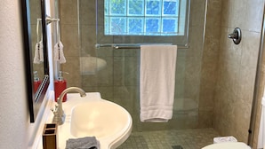 Ein Badezimmer mit Duschkabine, Waschbecken, Toilette und Spiegel.