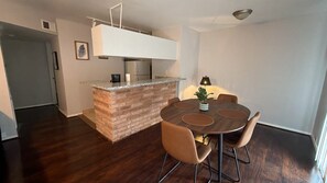 Una cocina moderna con una isla de ladrillo, un comedor con una mesa redonda y sillas, y un refrigerador.