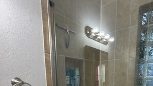 Een douche met een glazen deur, een handdoekhouder en een glazen douchecabine.