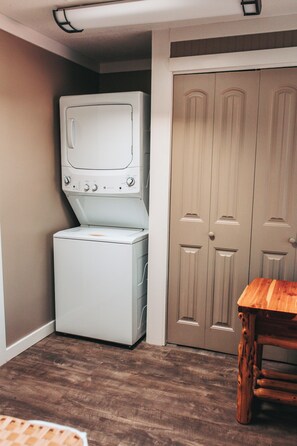 A laundry room with a washing machine and dryer, a wooden table, and a set of double doors.