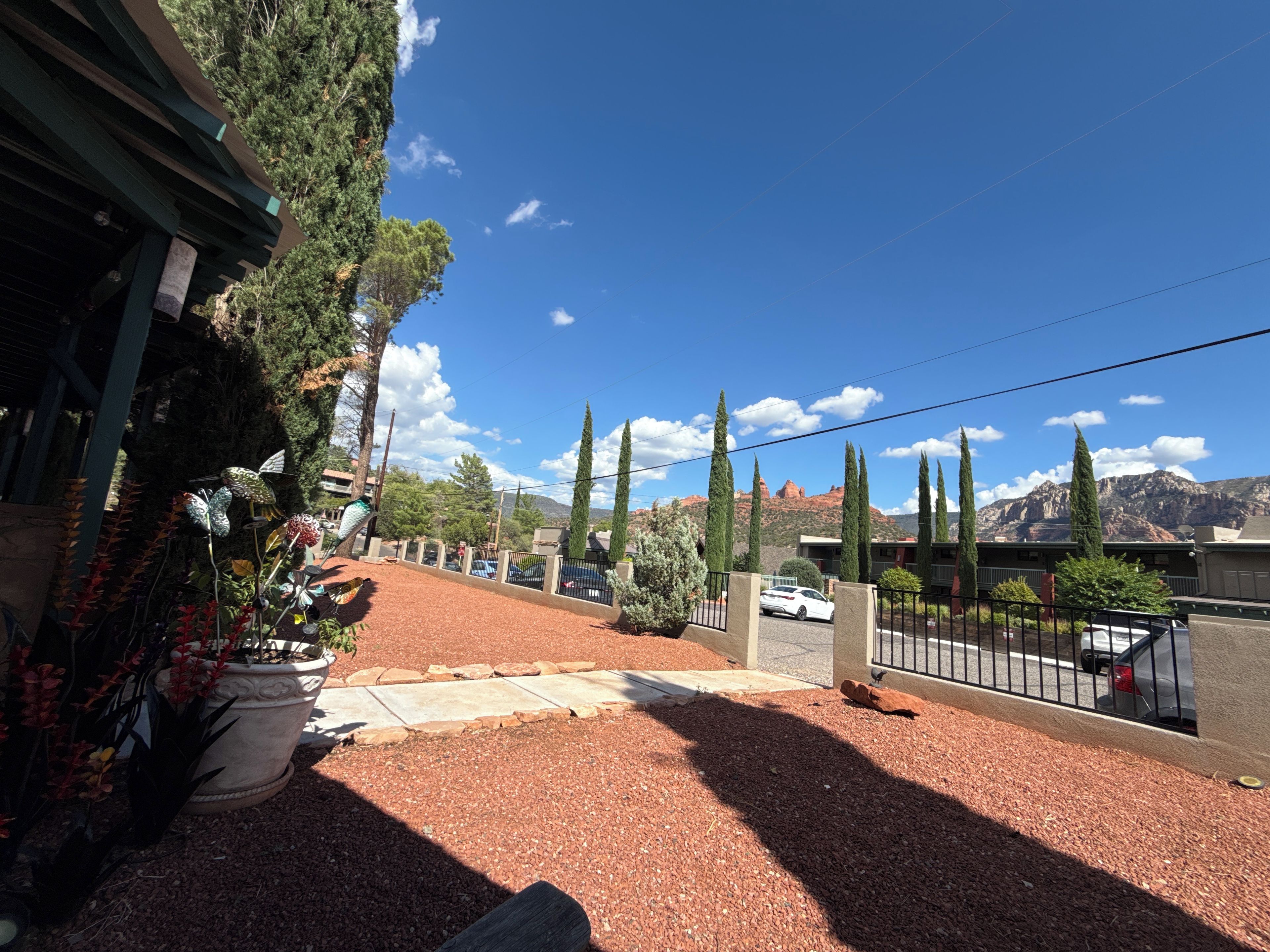 A residential area with a paved driveway, potted plants, and a view of distant mountains.