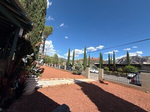 A residential area with a paved driveway, potted plants, and a view of distant mountains.