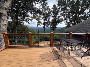 A wooden deck with a metal railing, a table, and chairs, overlooking a mountainous landscape. - Adagio 2: Luxury 2-bd 1-ba apt with stunning views close to Little River Canyon. (Gaylesville)
