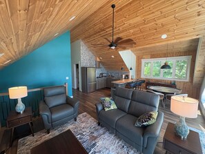 A spacious living area with a high ceiling, a kitchen, and a dining area.