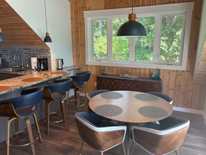 A modern kitchen with a central island, bar stools, and a dining table with chairs. - Adagio 2: Luxury 2-bd 1-ba apt with stunning views close to Little River Canyon. (Gaylesville)