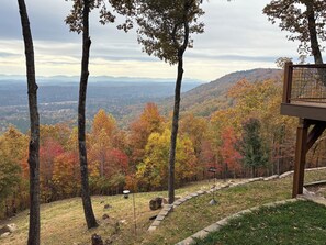 A view from a wooden deck overlooking a forested valley with autumn foliage.
