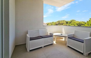 A balcony with two wicker sofas and a small table, a clear view of trees and a blue sky. - 2 bedroom cozy apartment in Povljana (Povljana)
