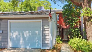 Une maison de plain-pied avec un garage, une partie en briques rouges et un arbre au premier plan.