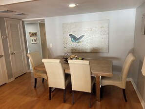 A dining area with a wooden table, four chairs, and a butterfly artwork on the wall.