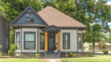 A two-story house with a gabled roof, a front porch, and a small front yard.