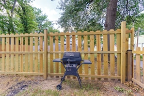 Un barbecue devant une clôture en bois.