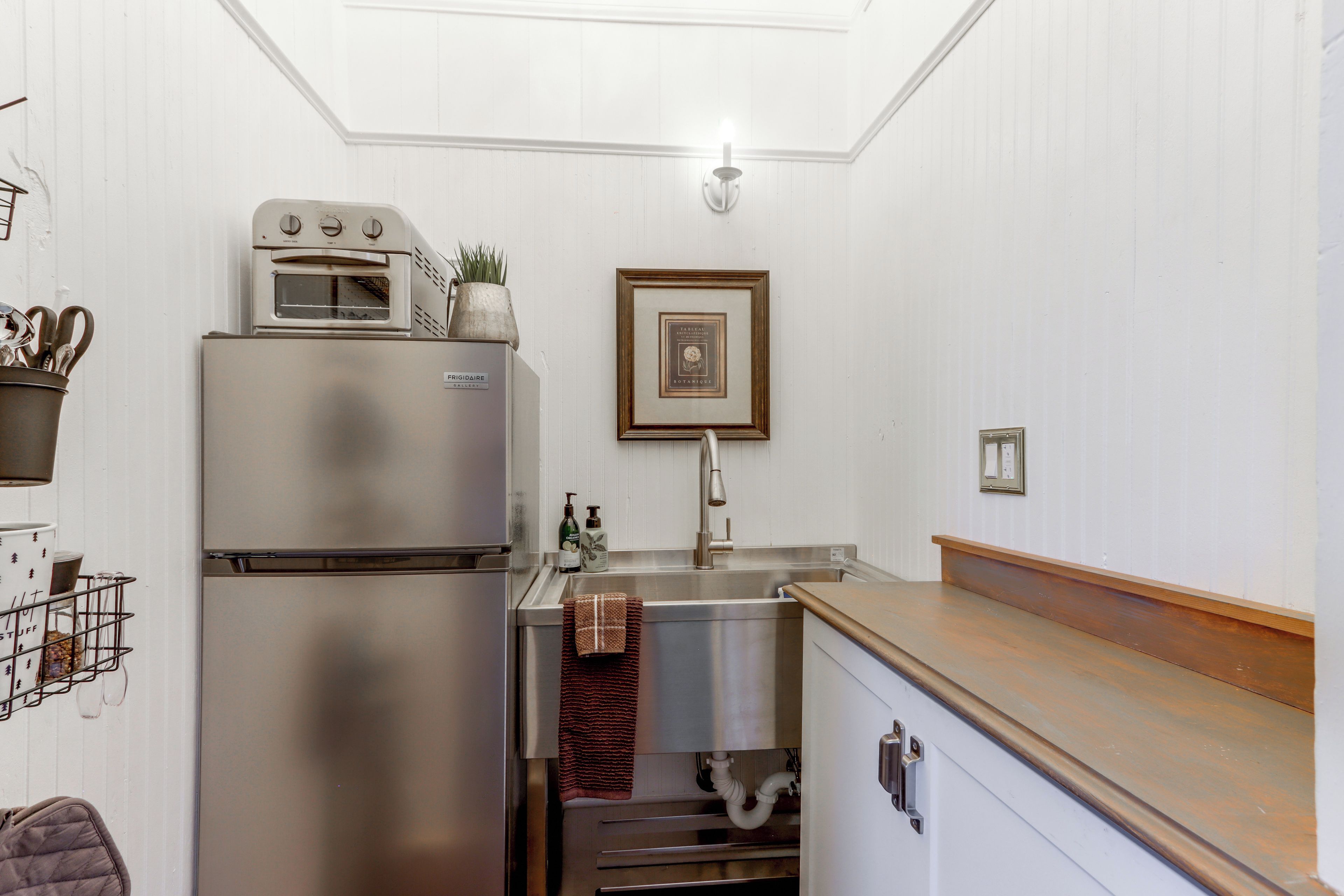 A compact kitchen with a built-in oven, a sink, and a wooden countertop.