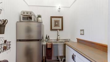 A compact kitchen with a built-in oven, a sink, and a wooden countertop.