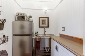 Une cuisine compacte dotée d’un four encastré, d’un évier et d’un plan de travail en bois.