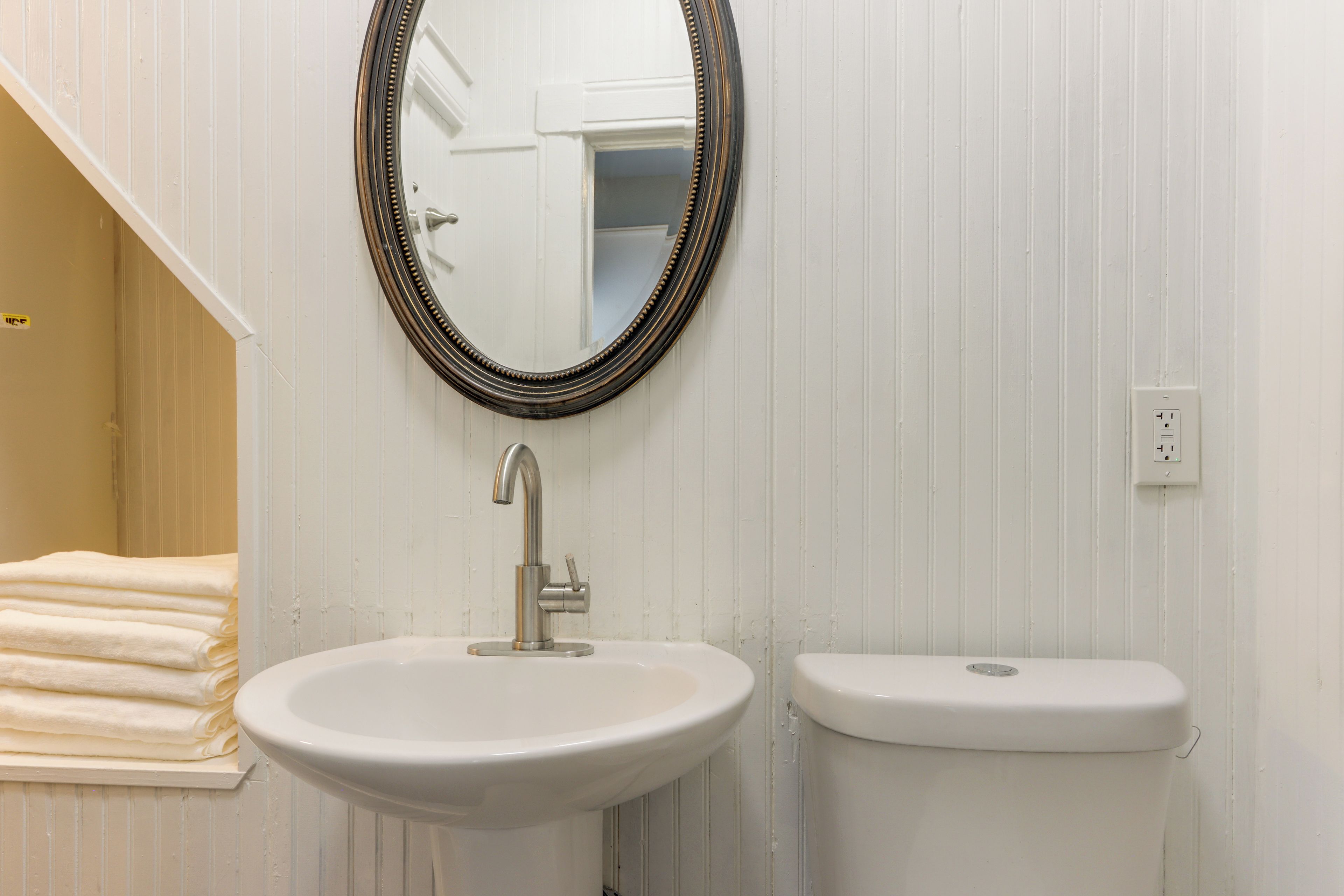 A bathroom with a white sink, a mirror with a decorative frame, and a white toilet.