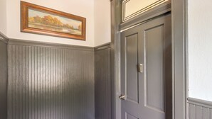 A room with a dark wooden door, a framed landscape painting on the wall, and a white trim around the door. - Walk Everywhere! Downtown Fort Smith Duplex (Fort Smith)