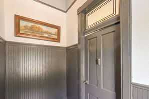 A room with a dark wooden door, a framed landscape painting on the wall, and a white trim around the door. - Walk Everywhere! Downtown Fort Smith Duplex (Fort Smith)