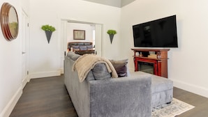A living room with a grey sofa, a flat-screen TV, and a fireplace. - Walk Everywhere! Downtown Fort Smith Duplex (Fort Smith)