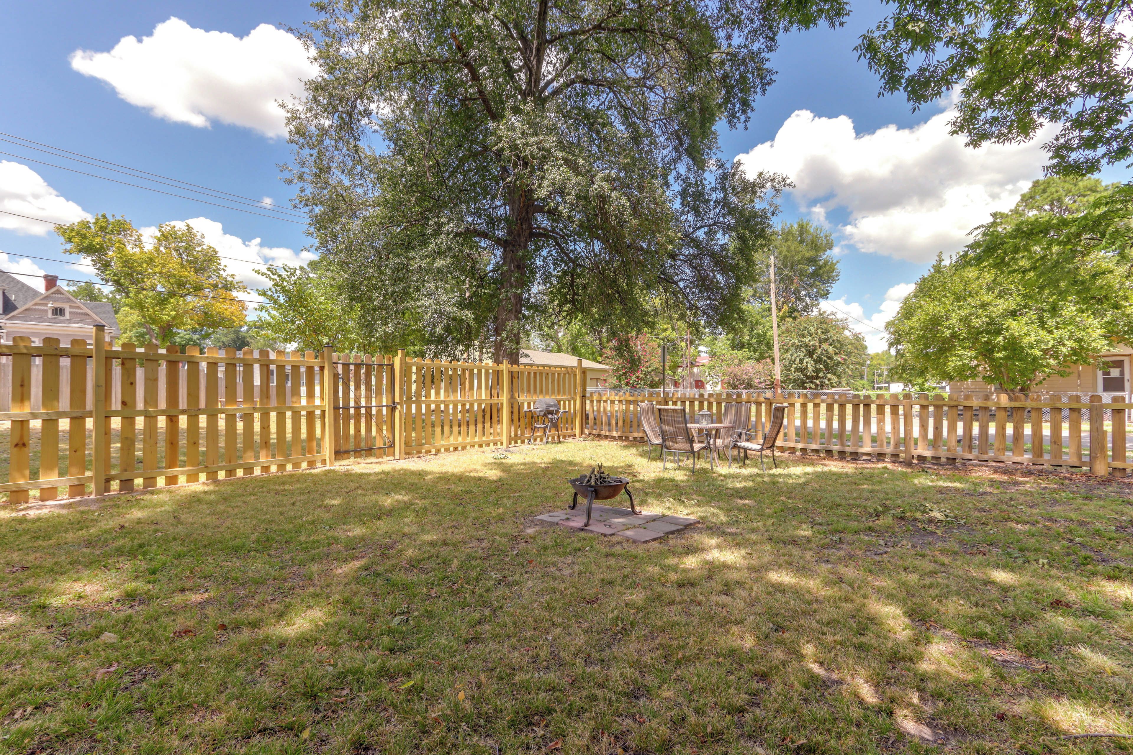 Un jardin avec une clôture en bois, un foyer extérieur et du mobilier de jardin.